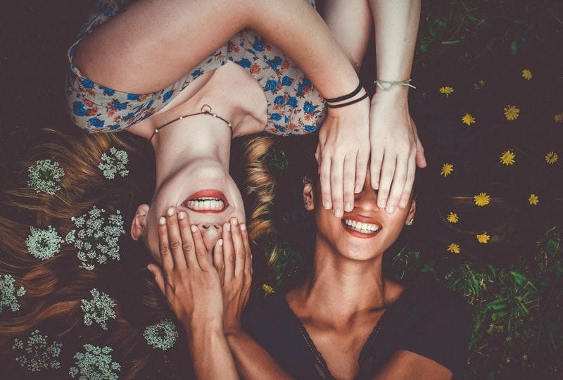 igualdad de géneros dos chicas jóvenes estiradas en el suelo de boca para arriba y tapándose los ojos mutuamente
